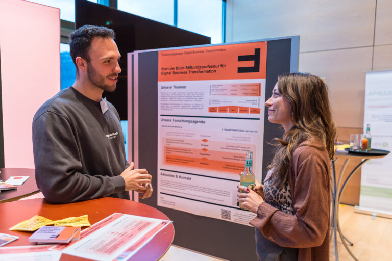 Zwei Menschen unterhalten sich vor einem Banner der FHV