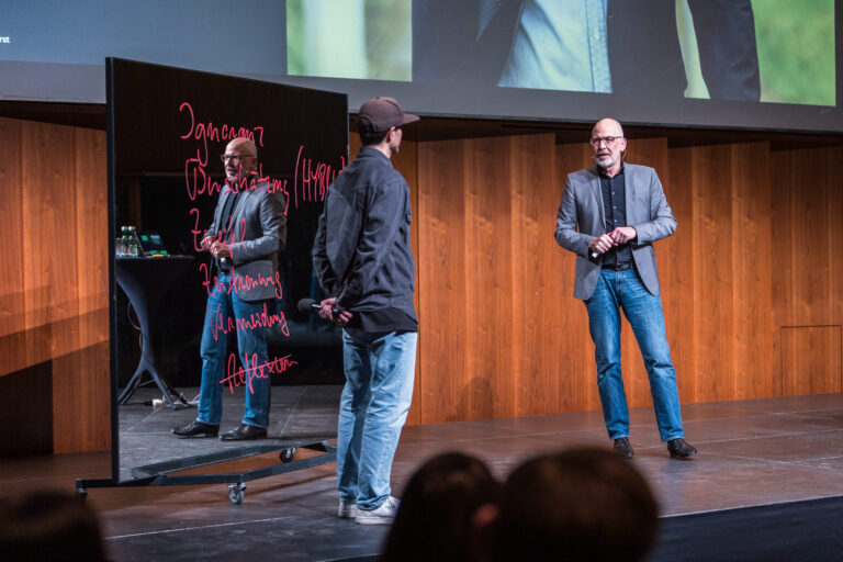 Zwei Menschen sprechen über unternehmerische Misserfolge auf einer Bühne