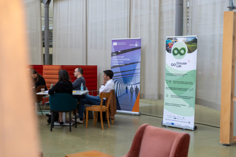 Menschen die einem Vortrag zuhören und an einem Tisch sitzen