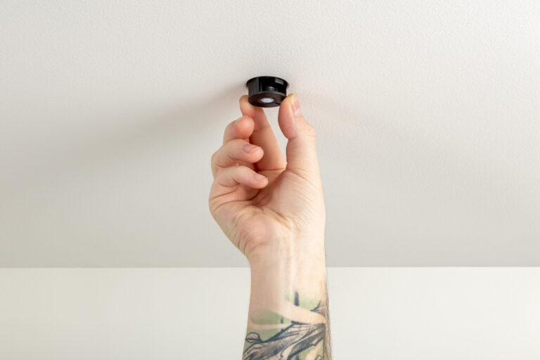 Eine Hand montiert den Bewegsungsmelder